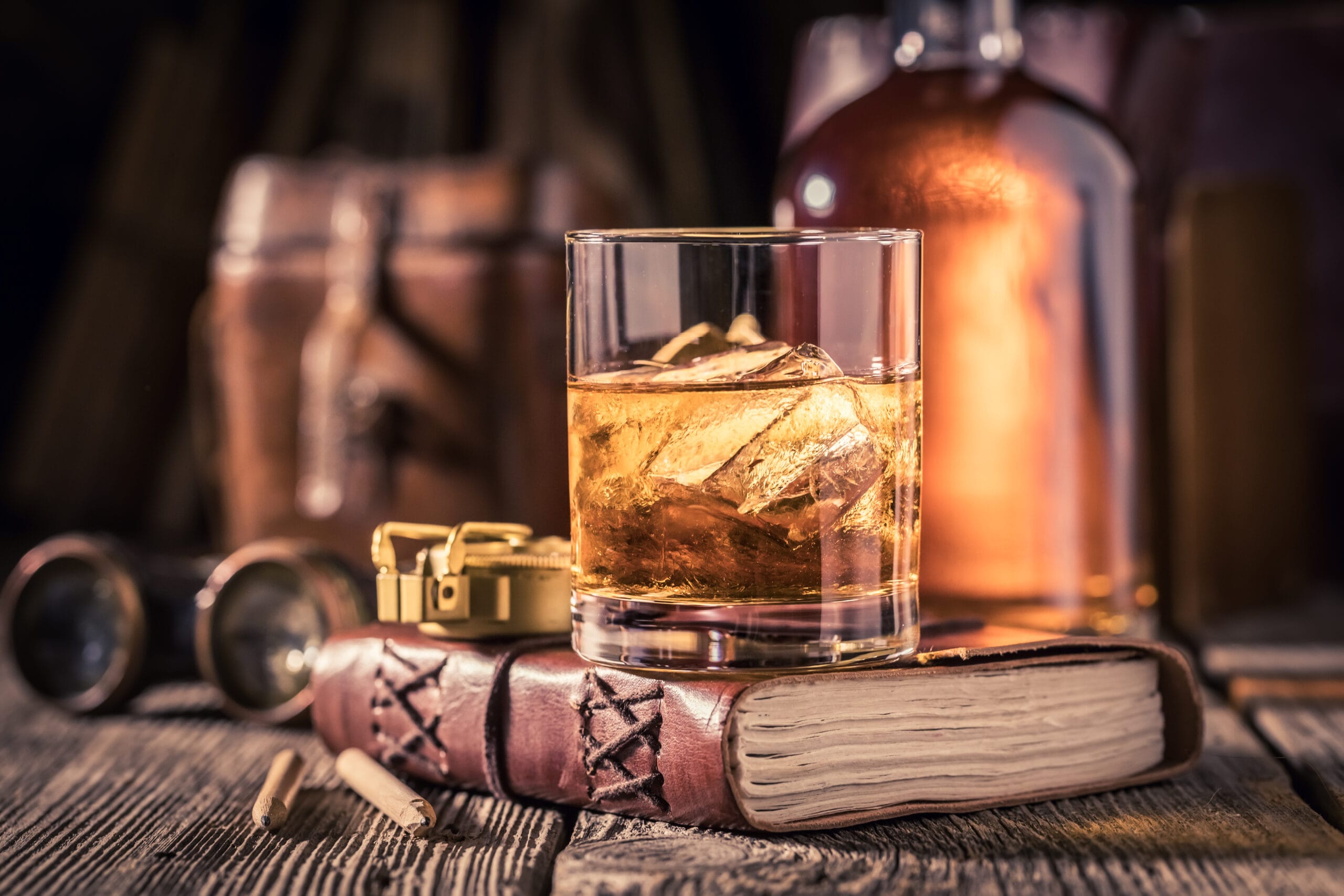 Closeup of whisky with ice on old journal Closeup of whisky with ice on old journal